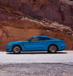 a blue sports car parked in front of a mountain