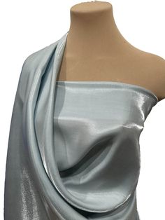 a mannequin wearing a silver dress on top of a white dummy with one arm wrapped around it