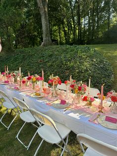 a long table is set up with pink and red centerpieces, candles, and plates