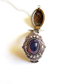 Dragon's breath is sometimes called Mexican glass fire opal, it's a handmade stone that is a hot redcolor with bright blue reflections. Stunning. Locket size :35 mm x 20 mm that opens to hold 4 photos The dragon breath stone is 14x10 mm across, with a silver frame setting surrounding the jewel. You can put a photo, smudge solid perfume or lip balm in the locket, or just wear empty :) The opal is a deep fuschia red with blue fleck. The antique silver plated floral engraved locket is 35x20mm. The Birthstone Medallion Locket Necklace As A Gift, Medallion Locket Necklace With Birthstone For Gift, Antique Round Pendant Jewelry As Gift, Amber Pendant Locket Jewelry, Vintage Gemstone Jewelry For Memorial, Vintage Locket Jewelry As A Gift For Her, Vintage Gemstone Jewelry For Gift, Vintage Locket Jewelry Gift For Her, Vintage Locket Jewelry As Gift For Her