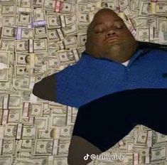 a man laying on top of a bed covered in lots of dollar bill bills with his eyes closed