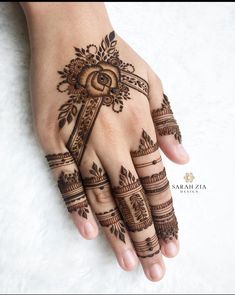 a woman's hand with henna tattoos and a cross on the middle finger