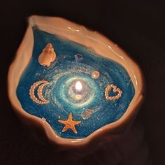 a candle is lit in a bowl with shells and other things on it that look like an ocean scene