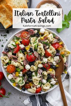 italian tortellini pasta salad in a white bowl with a wooden spoon on the side