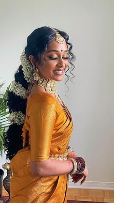 a woman in an orange sari is smiling and holding her hand on her hip