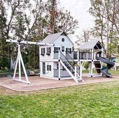 a white house with a swing set and slide in the yard next to some trees