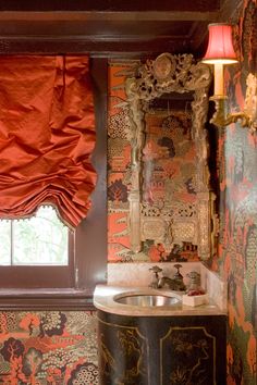 a bathroom with a sink, mirror and red curtained window in it's corner