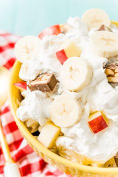 a bowl filled with fruit and whipped cream on top of a checkered table cloth