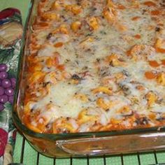 a casserole dish with cheese and vegetables in it on a green tablecloth