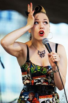 a woman holding a microphone up to her head while wearing a dress with tattoos on it