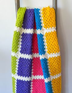 a multicolored crocheted blanket hanging on a hook