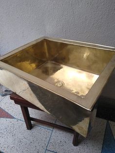 a large metal sink sitting on top of a wooden stand in front of a wall