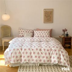 a bed with pink and white flowers on it in a room next to a chair