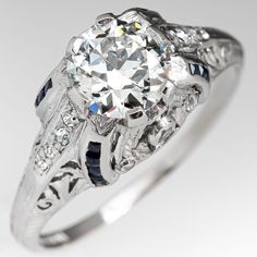 This beautiful circa 1930s engagement ring is centered with a 1.04 carat round transitional cut diamond set into a six-prong head. The ring features a pierced design, engraved with wheat motifs and bordered with milgrain edging. The ring is accented with 14 round single cut diamonds and 16 square French cut lab created sapphires. The ring measures 8.8mm at the top, rises 7.4mm above the finger, and is currently a size 7.75. We offer complimentary resizing to fit. Antique Diamond Engagement Rings, Antique Diamond Rings, Art Deco Engagement, Aquamarine Jewelry, Beautiful Engagement Rings, Deco Engagement Ring, Art Deco Engagement Ring, Antique Diamond, March Birth Stone