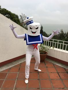 a person dressed up as a sailor in front of a balcony with a potted plant