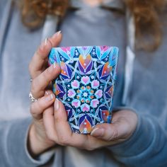 a woman is holding a small box with designs on it and her hands are clasped together