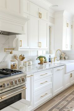 a kitchen with white cabinets and gold trim on the stove top, along with an area rug