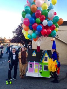 some people are standing in front of a house with balloons