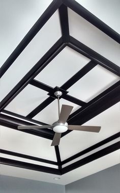 a ceiling fan mounted to the side of a white and black ceiling in an empty room