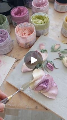 a person is painting flowers on a piece of paper with acrylic pastes