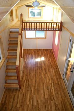 the inside of a tiny house with wood floors and stairs leading up to an upstairs loft