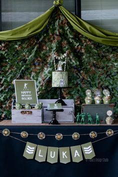 a table topped with cake and cupcakes next to a wall covered in leaves