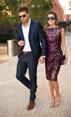 a man and woman are walking down the street holding hands while dressed in formal attire