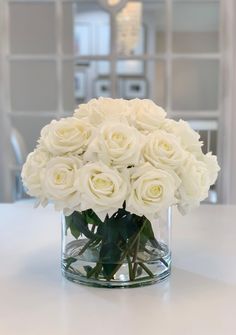 a vase filled with white roses on top of a table