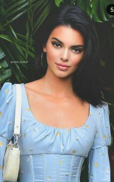 a woman wearing a blue dress and holding a white purse