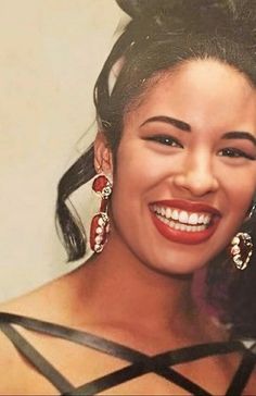 a woman smiling with her hair in a bun and earrings on top of her head