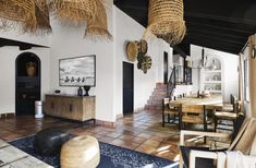 a living room filled with furniture and lots of wicker baskets hanging from the ceiling