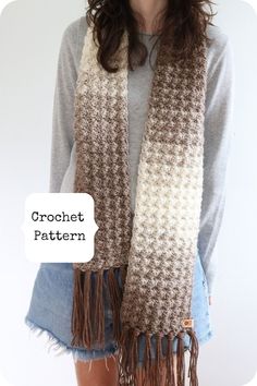 a woman wearing a brown and white crochet scarf with fringes on it