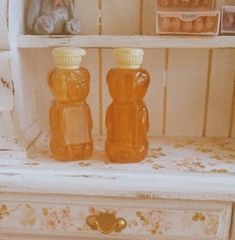 two glass bottles sitting on top of a white dresser next to a teddy bear and other items