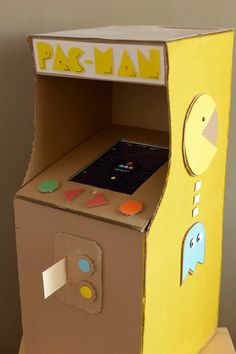 an arcade machine made out of cardboard sitting on top of a wooden table next to a wall