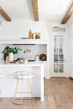 a white kitchen with gold bar stools