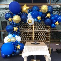 blue and gold balloon arch with stars on it at a table in front of a window