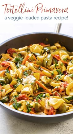 a pan filled with pasta and vegetables on top of a table