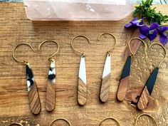 seven pairs of earrings are sitting on a table next to some flowers and a rock