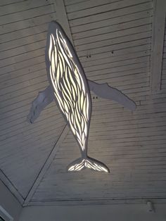 a light that is on the side of a building with a whale shaped object hanging from it's ceiling