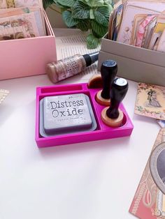 there is a pink tray with some stamps on it and two ink pens in the holder