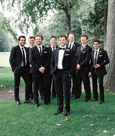 a group of men standing next to each other on top of a lush green field