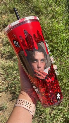 a person holding up a red cup with the image of elvis presley on it in their hand