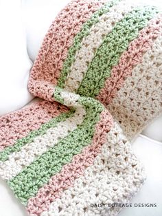 a crocheted blanket sitting on top of a white couch next to a pillow