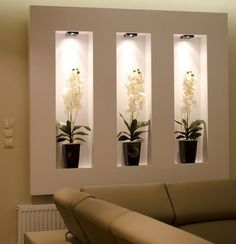 three planters with white flowers in them are on the wall above a leather couch