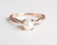 a pearl and diamond ring on a white surface