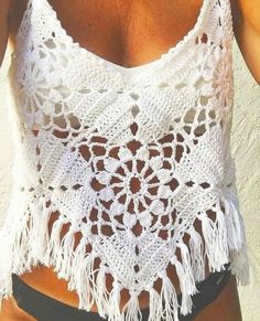 a woman wearing a white crochet tank top and black shorts with her hand on her hip