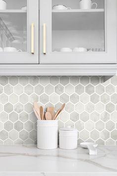 a kitchen counter with white cabinets and wooden utensils