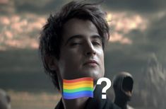 a man holding a rainbow flag in front of his face with the question mark on it