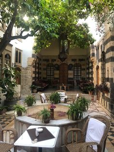 an outdoor dining area with tables and chairs, potted plants on either side of the table