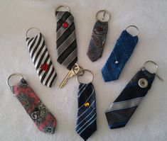 six different neck ties are arranged in a circle on a white surface, with one keychain hanging from the middle